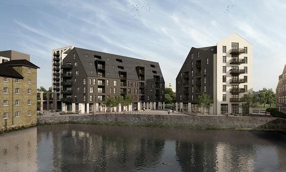 A CGI of Town Quay with water in the foreground and two apartment blocks behind. The building on the left is dark grey with a sloping roof. The building on the right is dark grey and light grey on the right-hand-side, with balconies overlooking the water.